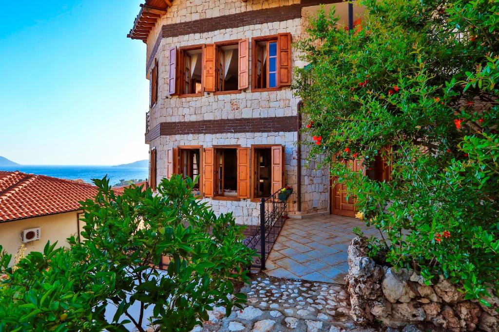a large stone house with a door and trees at Çınarlar Apart KC Blok in Kaş