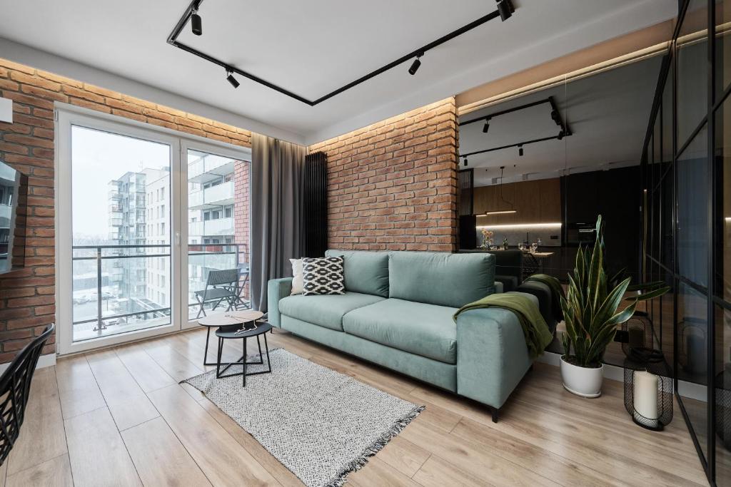 un soggiorno con divano verde e parete in mattoni di Lux Apartment Browary Wrocławskie by Renters a Breslavia