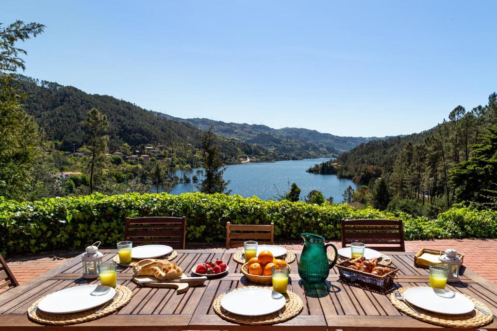 a wooden table with food and a view of a lake at Gerês Mountain Lake Views in Geres
