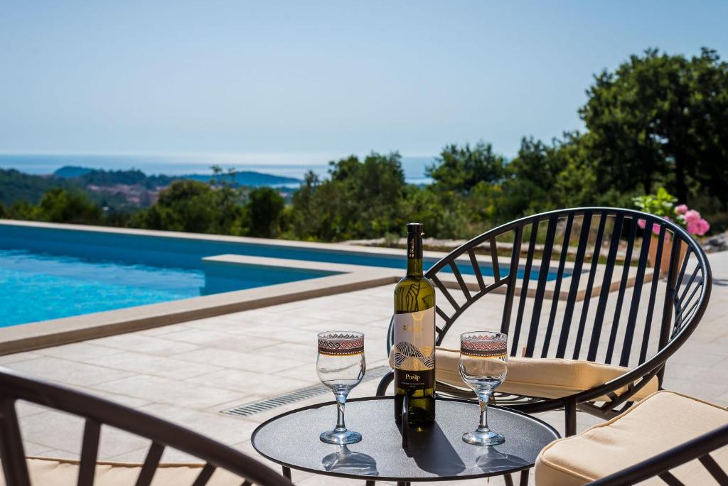a bottle of wine sitting on a table with two glasses at Villa Rubea in Cavtat