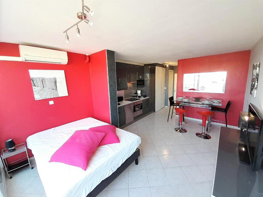 - une chambre avec un mur rouge et un lit avec un oreiller rose dans l'établissement Studio Village Naturiste Pepperoni, au Cap d'Agde