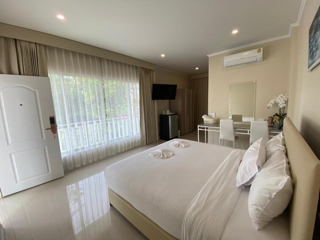 a bedroom with a large white bed and a table at Siri Ville Hotel in Si Sa Ket