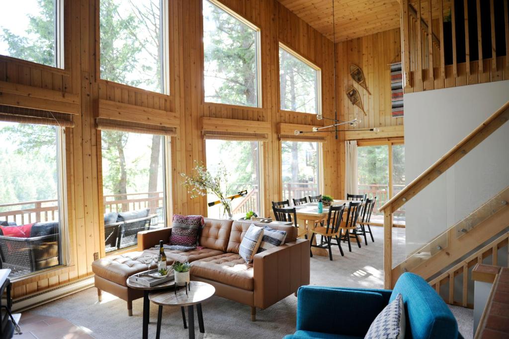 Mid Century Modern Mountain Cabin في إنفيرمير: غرفة معيشة مع أريكة وطاولات ونوافذ
