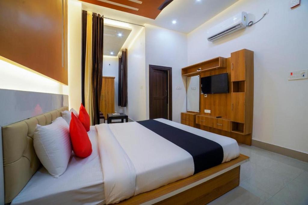a bedroom with a bed with red pillows and a television at Hotel Anand International in New Delhi