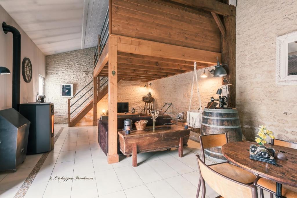 Zimmer mit Holzwänden und Tischen sowie einer Treppe in der Unterkunft L’échappée Vendéenne in Saint-Aubin-la-Plaine