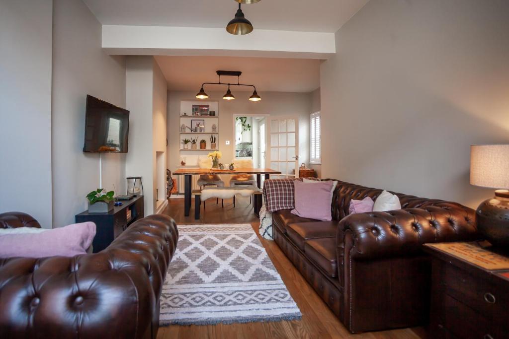 a living room with brown leather couches and a table at St Owen's Terrace by RentMyHouse in Hereford