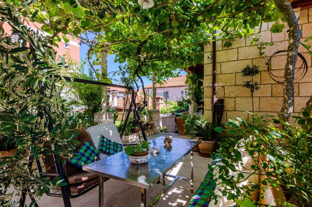 una mesa y sillas en un jardín con plantas en Apartments & Room Frane, en Dubrovnik