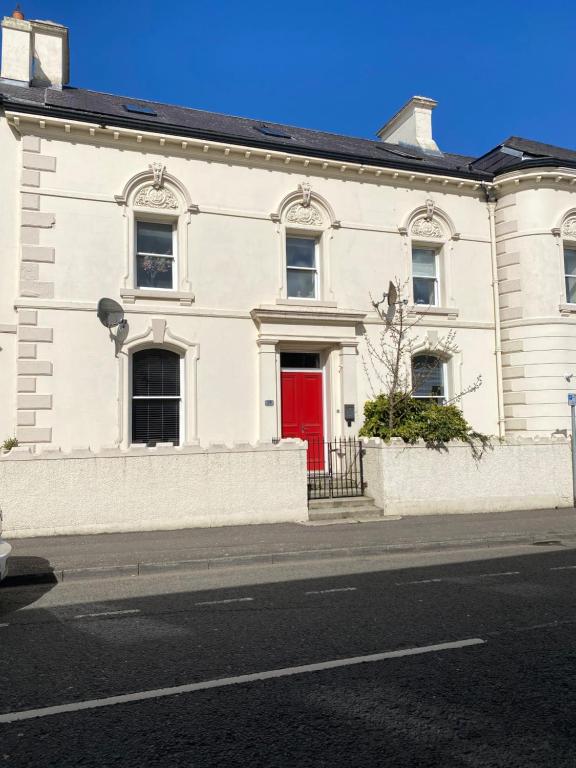 a white building with a red door on a street at Chapel View in Ballycastle