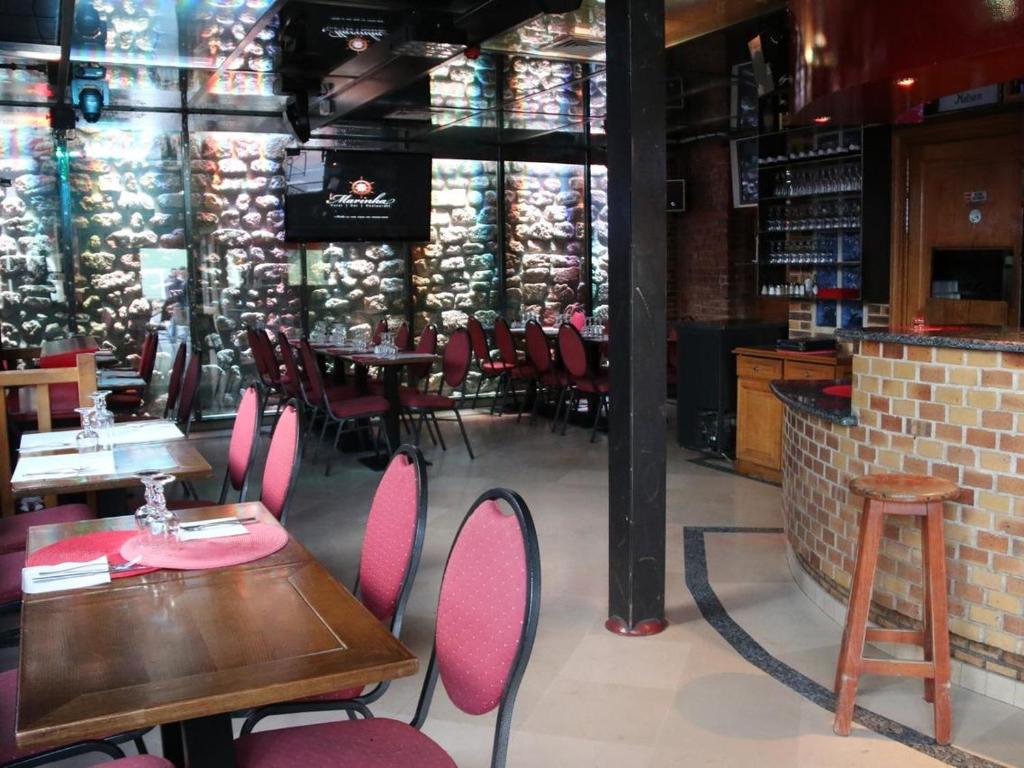 a restaurant with tables and chairs and a brick wall at Marinha Hotel in Gentilly
