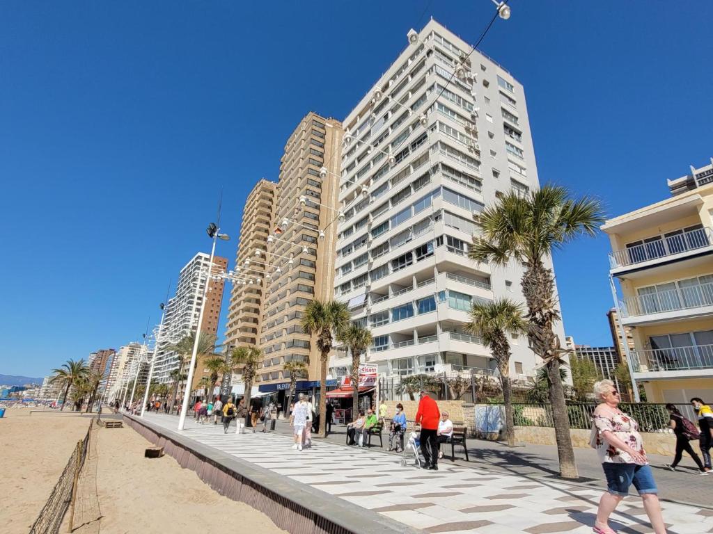 pessoas andando na praia em frente a edifícios altos em Tor Serena-Fincas Benidorm em Benidorm