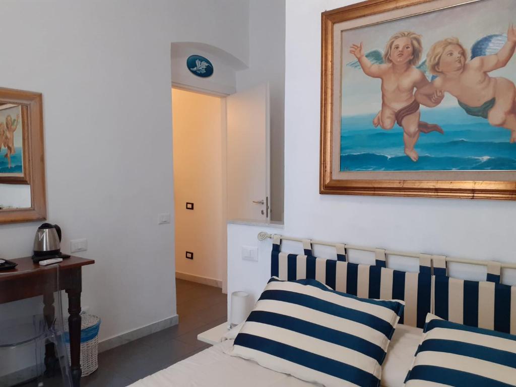 a bedroom with a painting above a bed with striped pillows at L'Angelo Blu in La Spezia
