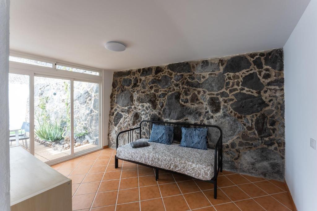 a room with a stone wall and a bench with blue pillows at villa del mar puerto del carmen in Puerto del Carmen