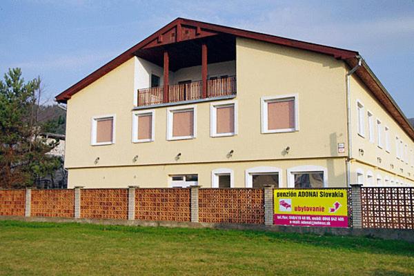 a large white house behind a brick fence at Penzión* ADONAI SLOVAKIA in Banská Bystrica