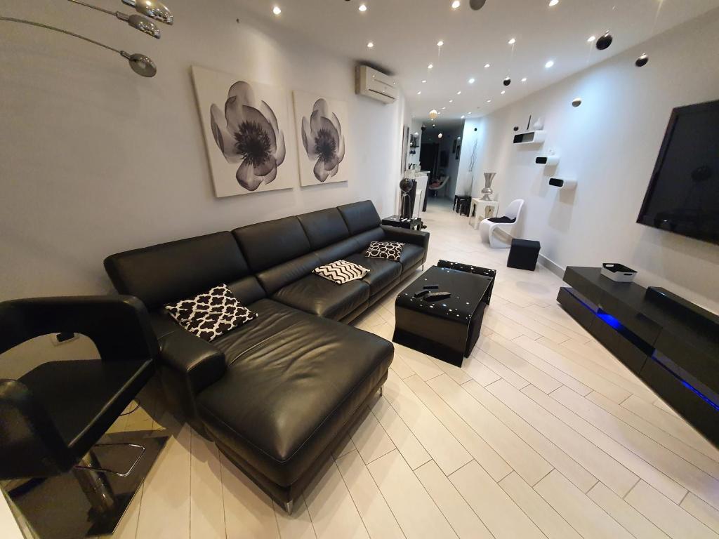 a living room with a black leather couch and a television at Casa Vacanza Pozzuoli in Pozzuoli