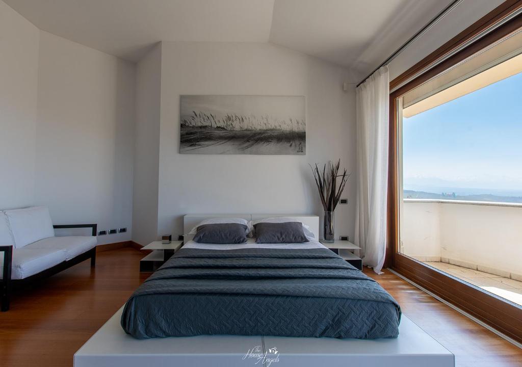 sypialnia z dużym łóżkiem i dużym oknem w obiekcie LANGA SUNSET VILLA w mieście Belvedere Langhe
