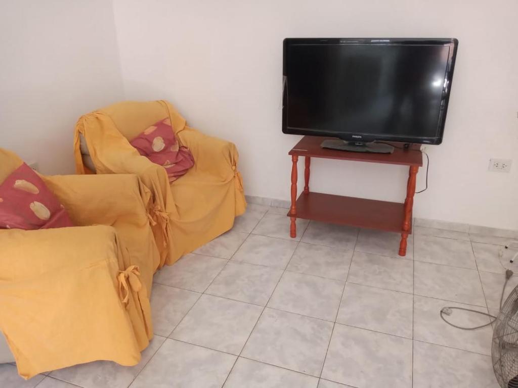 ein Wohnzimmer mit 2 Stühlen und einem Flachbild-TV in der Unterkunft Apart Belgrano in Corrientes