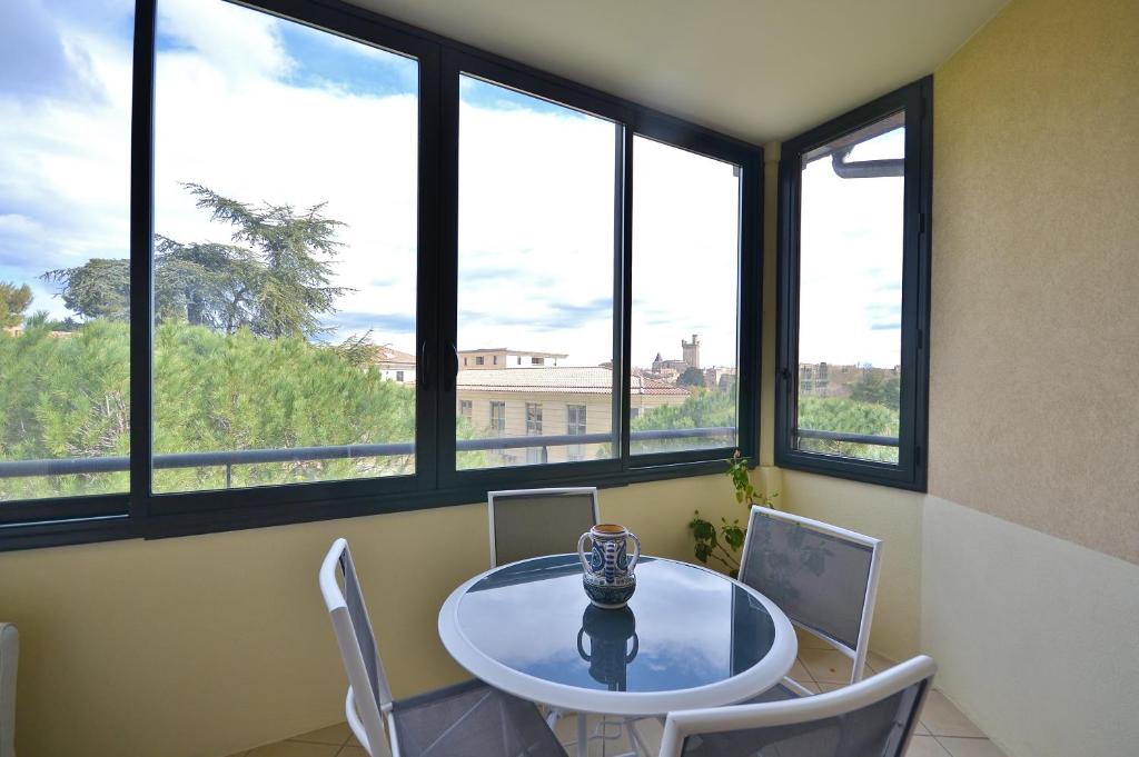 comedor con mesa y 4 ventanas en Appartement dans résidence avec piscine et parking en Uzès