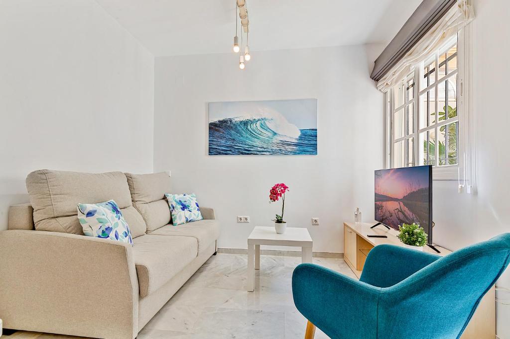a living room with a couch and two blue chairs at Apartamento con patio a 1 minuto de la playa in Fuengirola