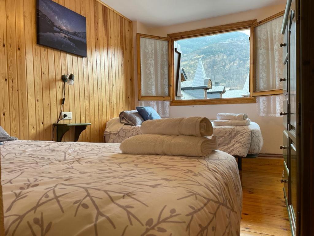 une chambre avec deux lits et une grande fenêtre dans l'établissement Apartamento turístico Nievesol 24 - Benasque, à Benasque