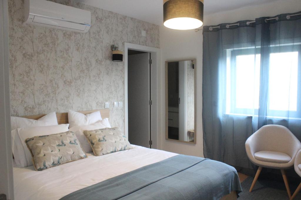um quarto com uma cama, uma janela e uma cadeira em Casa Dona Alzira em Arganil