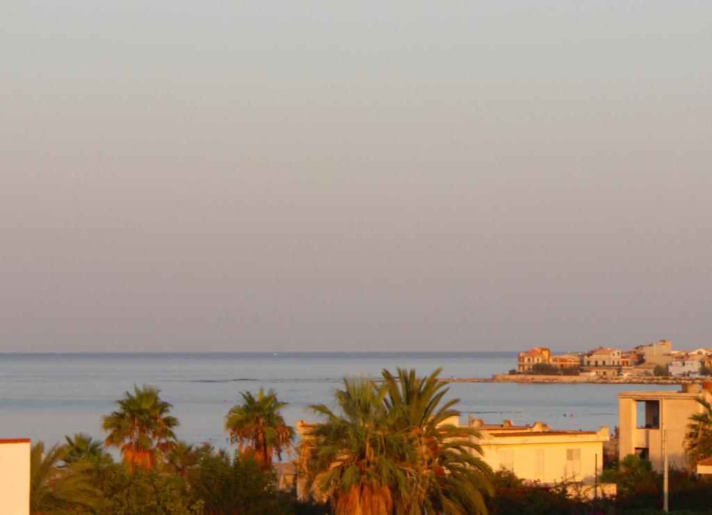 a view of the ocean and buildings and palm trees at La Casa dei Girasoli in Marzamemi