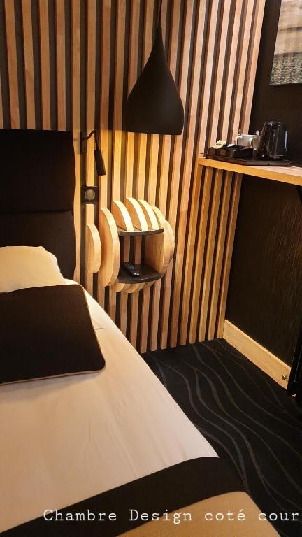 a bedroom with a bed and a lamp and a chair at Hôtel Les Brises in La Rochelle