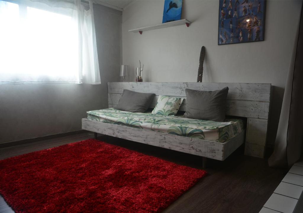 - un lit dans une chambre dotée d'un tapis rouge dans l'établissement Un pied-à-terre au centre de Papeete, à Papeete