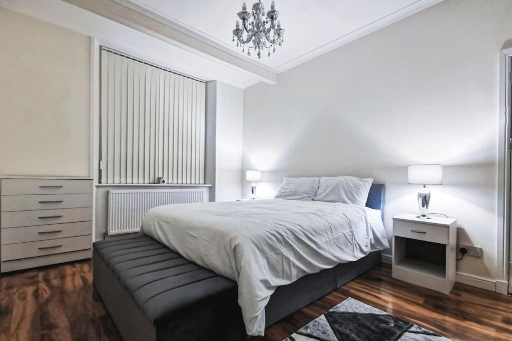 a white bedroom with a bed and a chandelier at Glasgow Southside: Cosy 2 Bedroom Apartment in Glasgow