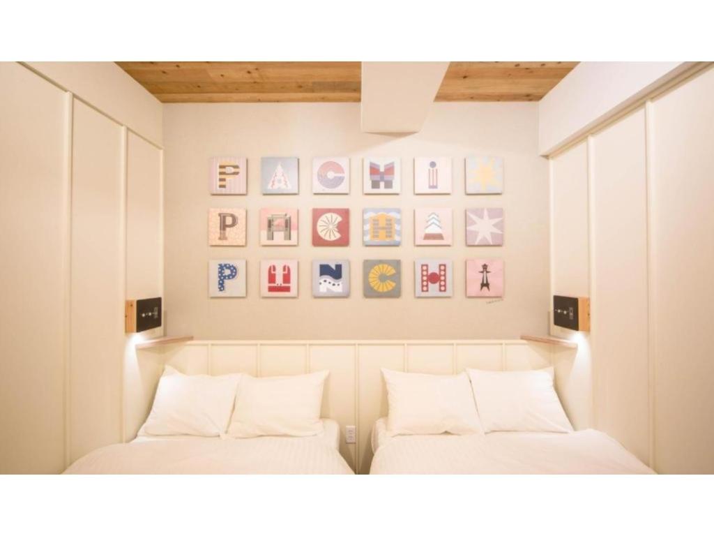 two beds in a room with pictures on the wall at Kamon Hotel Namba - Vacation STAY 37029v in Osaka