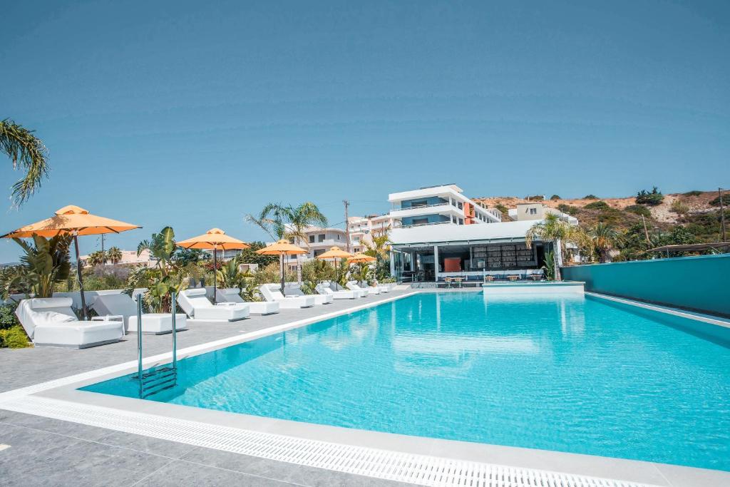 una grande piscina con sedie e ombrelloni di Mazoren Art Hotel a Faliraki