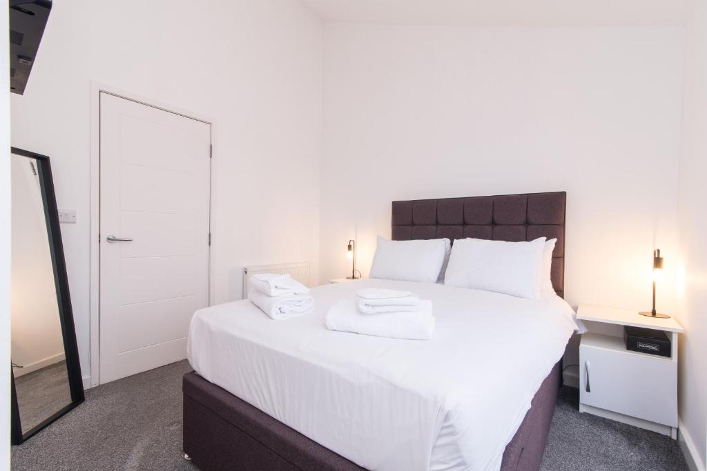 een slaapkamer met een groot wit bed en een spiegel bij Cricket View - Fabulous 1bed Apt near Trent Bridge Cricket Ground in Nottingham