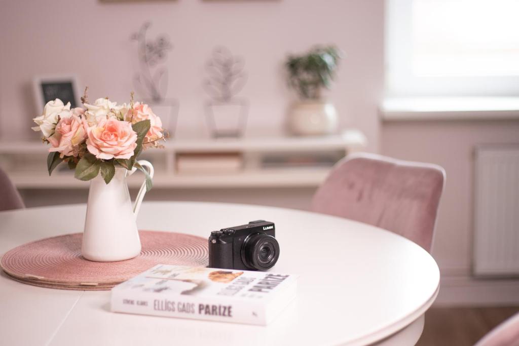 a camera sitting on a table with a vase of flowers at Provance Apartment in Liepāja