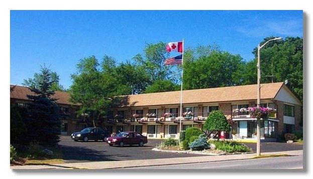 a hotel with a flag in front of a building at Heritage Inn & Suites in Niagara Falls