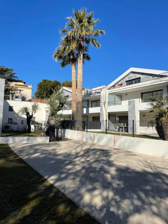 un bâtiment avec un palmier devant dans l'établissement T2 GARDEN BEACH, à Saint-Cyr-sur-Mer