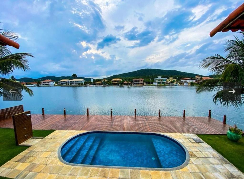 a swimming pool next to a body of water at Casa Cabo Frio in Cabo Frio