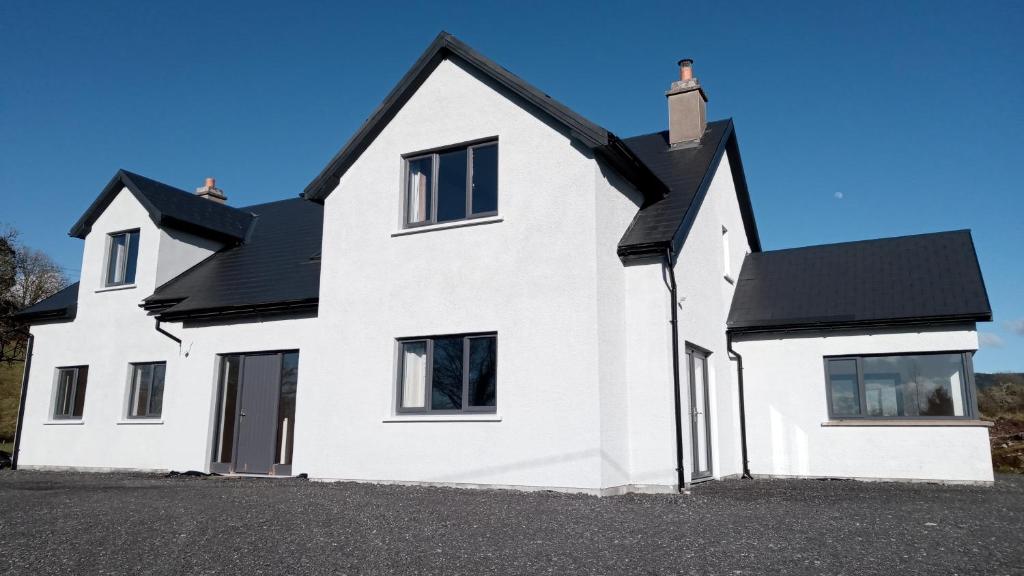 una casa blanca con techo negro en Geevagh Holiday Home en Geevagh