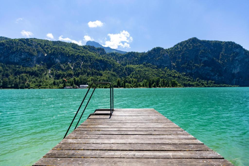 un muelle de madera en un lago con montañas en el fondo en Seegut Kübler, en Ort
