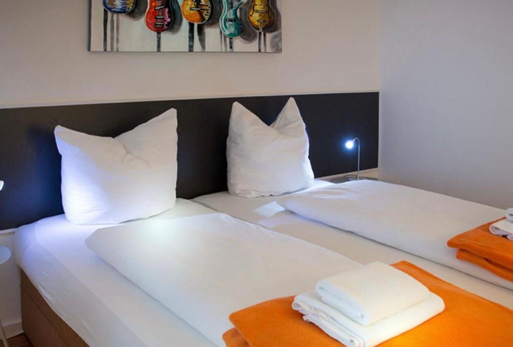 two beds in a room with white sheets and pillows at H&H Studio-Apartments im Zentrum jedes Apartment mit Küchenzeilen - 24h Check In in Greifswald