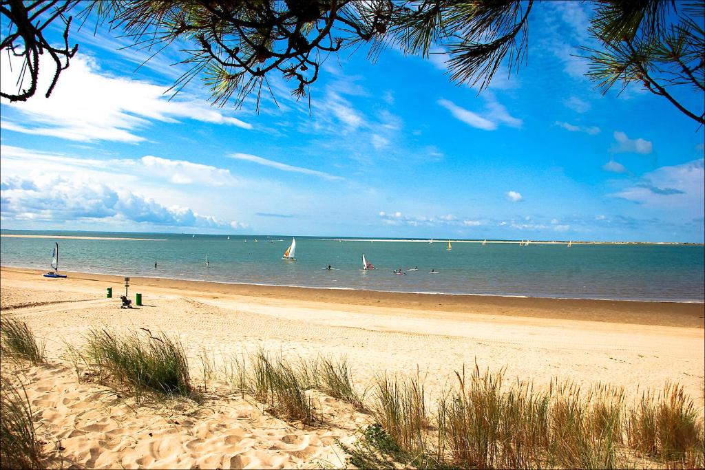 une plage avec des gens et des bateaux dans l'eau dans l'établissement Maison à La Palmyre, proche commerces et plages, aux Mathes