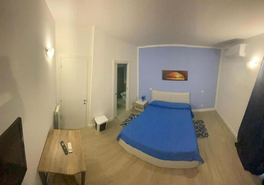 een slaapkamer met een blauw bed en een tafel bij Riviera Albachiara Anzio B&B in Anzio