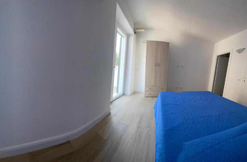 a bedroom with a blue bed and a window at Riviera Albachiara Anzio B&B in Anzio