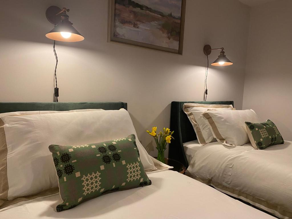 two beds in a bedroom with two lamps and flowers at Llandudno Boutique style seaside retreat with stunning views in Llandrillo-yn-Rhôs