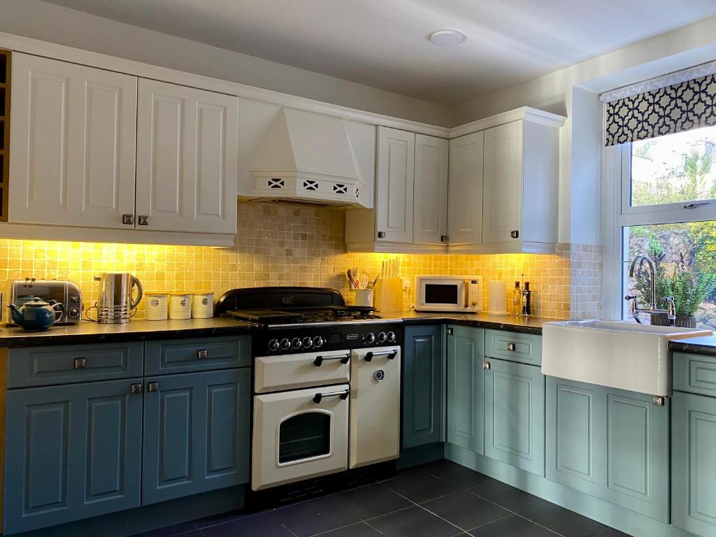 a kitchen with blue cabinets and white appliances at Llandudno Boutique style seaside retreat with stunning views in Llandrillo-yn-Rhôs