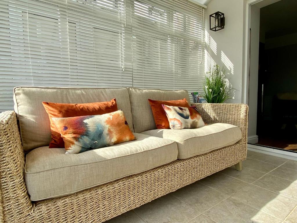 a wicker couch with pillows on it in a living room at Llandudno Boutique style seaside retreat with stunning views in Llandrillo-yn-Rhôs