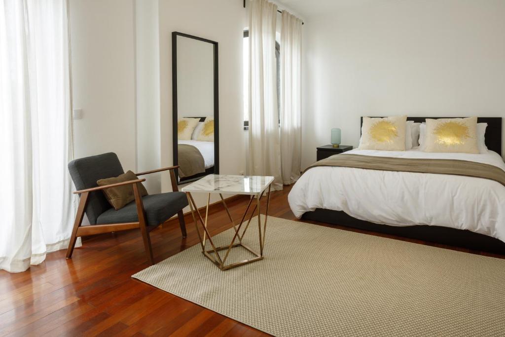 a bedroom with a bed and a chair and a mirror at Avenida in Elvas