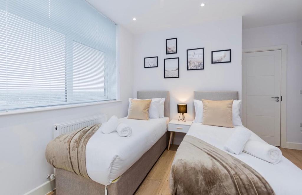 2 Betten in einem Schlafzimmer mit weißen Wänden und einem Fenster in der Unterkunft Elegant Central, Private Parking, Leisure, Contractor in Buckinghamshire