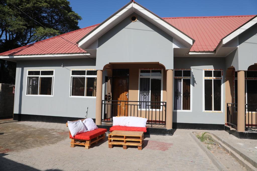 una casa con 2 sillas y techo rojo en PEARL LULU MODERN BNB Homestay, en Dar es Salaam