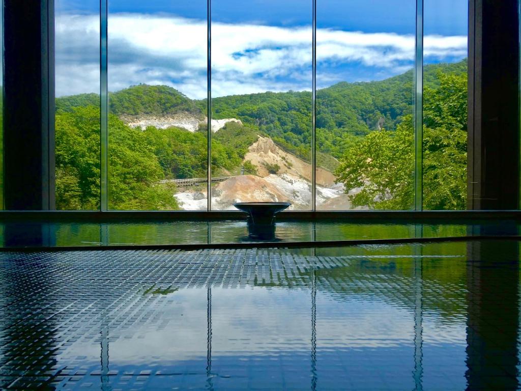 a room with a large window with a view of a mountain at Dai-ichi Takimotokan in Noboribetsu