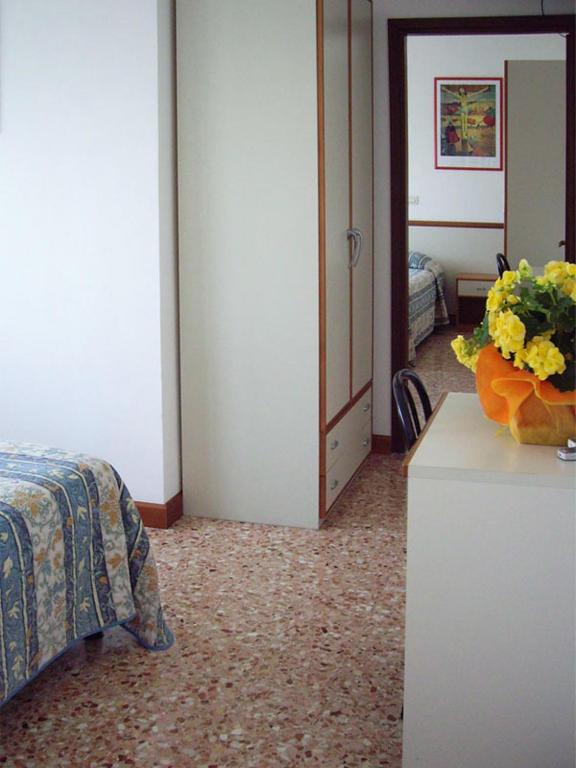 a bedroom with a bed and a vase of flowers on a counter at Hotel Maxim in Caorle