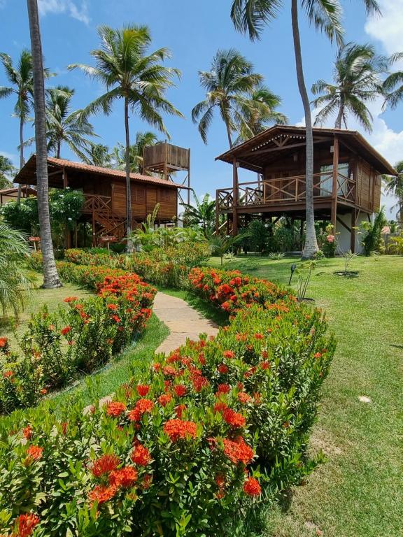 um resort com palmeiras e um jardim com flores em Chalés Bayern em Icaraí